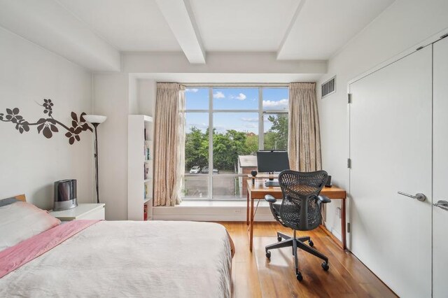 bedroom featuring visible vents, wood finished floors, and beam ceiling