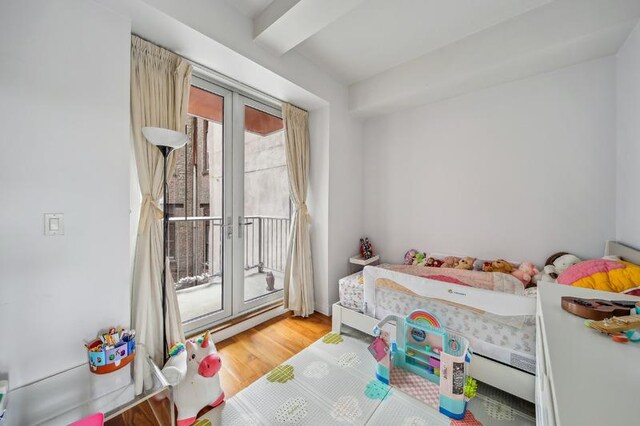 bedroom with access to exterior, baseboard heating, beamed ceiling, and light wood finished floors