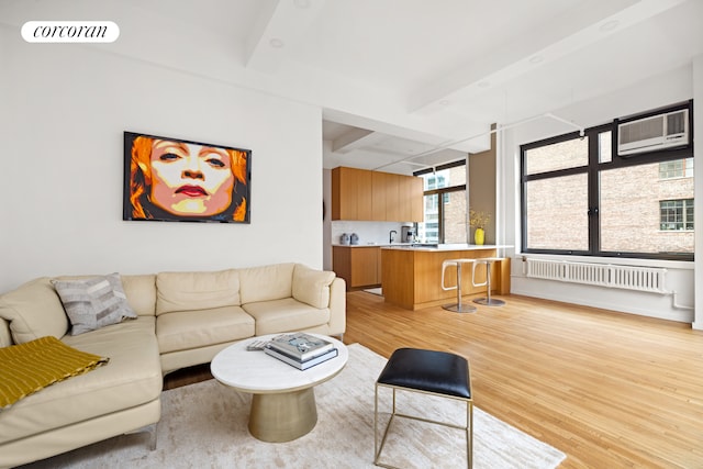 living area featuring visible vents, radiator, a wall unit AC, beamed ceiling, and light wood-style floors