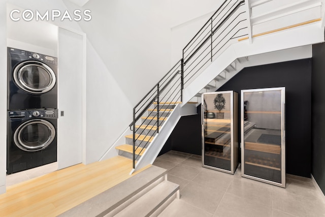 stairs with tile patterned floors and stacked washer and dryer