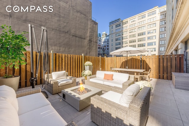 view of patio / terrace with a view of city, an outdoor living space with a fire pit, and fence