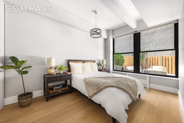 bedroom featuring baseboards, radiator heating unit, light wood-type flooring, beam ceiling, and an inviting chandelier