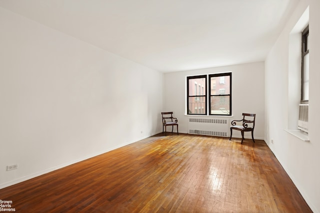 unfurnished room featuring radiator heating unit, baseboards, and wood-type flooring