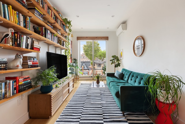 living area featuring light wood-style floors and an AC wall unit