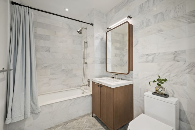 full bath featuring toilet, tile walls, vanity, and tiled shower / bath combo