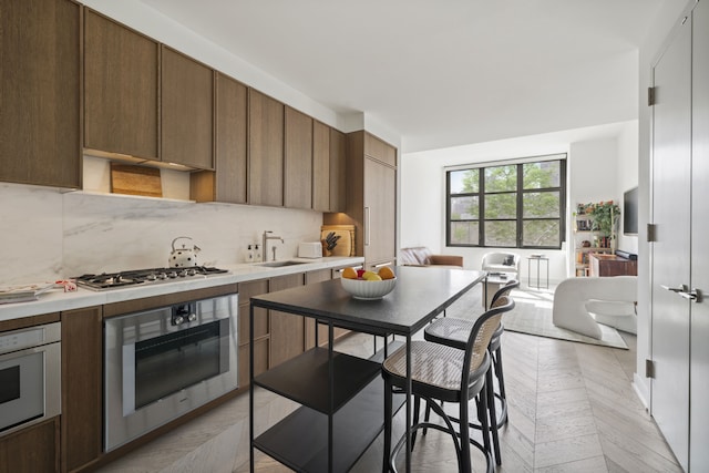 kitchen featuring a sink, open floor plan, appliances with stainless steel finishes, light countertops, and decorative backsplash