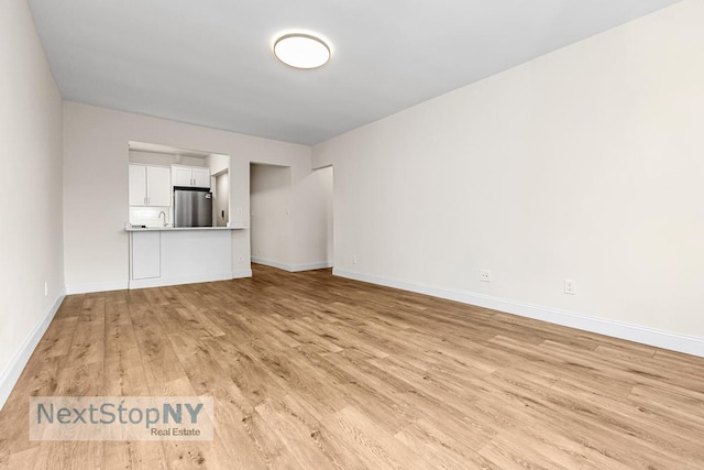 unfurnished living room featuring light wood-type flooring and baseboards