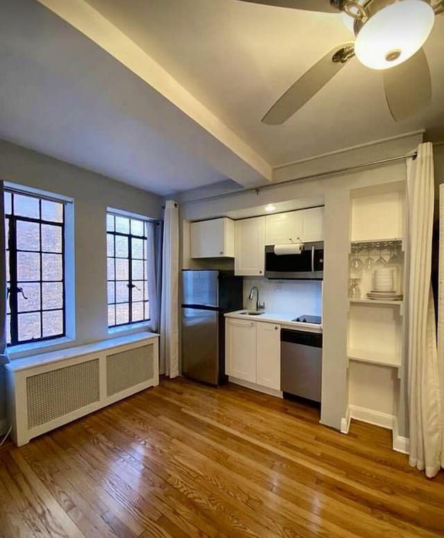 kitchen with stainless steel appliances, a sink, radiator heating unit, and wood finished floors