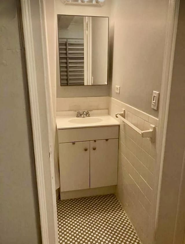 bathroom featuring tile walls, a wainscoted wall, and vanity