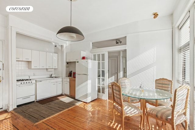 kitchen with visible vents, light wood-style flooring, a sink, backsplash, and white appliances