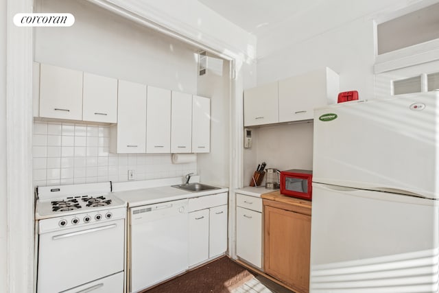 kitchen with a sink, white appliances, backsplash, and light countertops