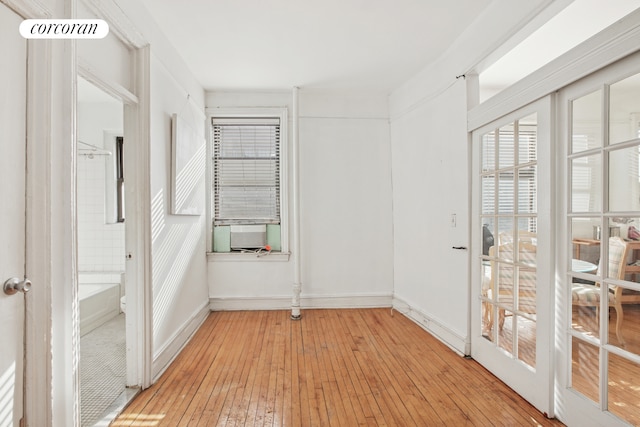 spare room featuring light wood-style floors, cooling unit, and baseboards