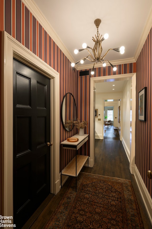 corridor featuring dark wood-style flooring, a notable chandelier, crown molding, baseboards, and wallpapered walls