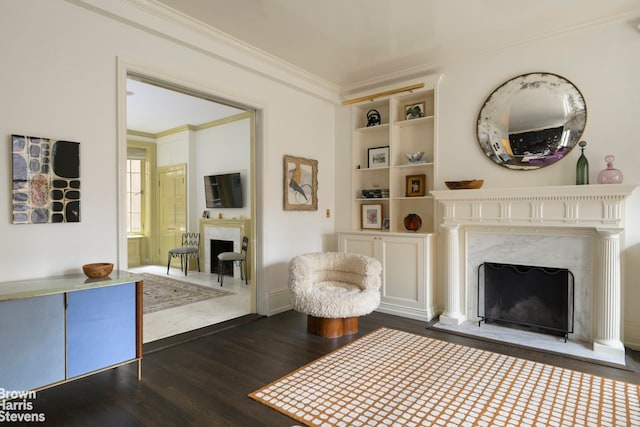 sitting room with a fireplace, ornamental molding, and dark wood finished floors