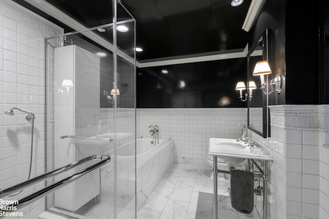 bathroom featuring marble finish floor, a garden tub, crown molding, a stall shower, and wainscoting