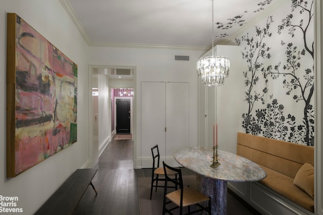 dining area featuring dark wood-type flooring, an inviting chandelier, visible vents, and crown molding