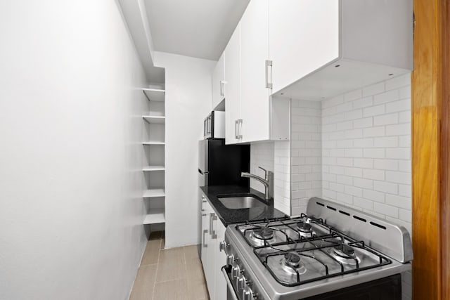 321 E 54th St Unit 2J, New York City, NY 10022 - kitchen with gas range oven, a sink, white cabinets, decorative backsplash, and freestanding refrigerator