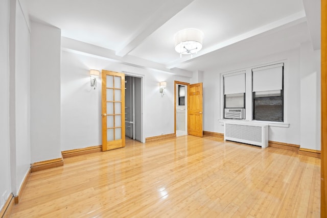 unfurnished room featuring radiator, beamed ceiling, baseboards, and hardwood / wood-style flooring