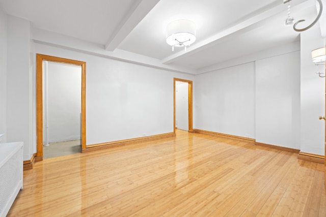 unfurnished room with beam ceiling, radiator, wood finished floors, and baseboards