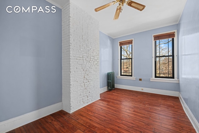 empty room with ceiling fan, baseboards, hardwood / wood-style floors, and radiator heating unit