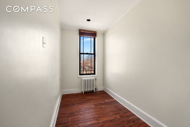 empty room featuring radiator heating unit, baseboards, and dark wood-style flooring