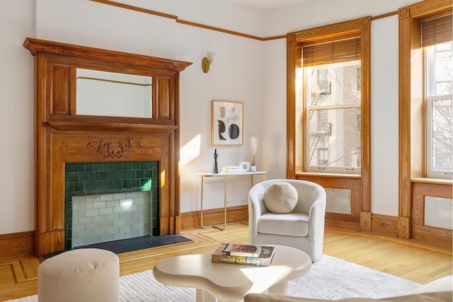 sitting room with baseboards, a tiled fireplace, and wood finished floors