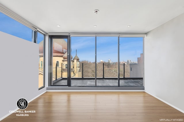 spare room featuring baseboards, wood finished floors, and floor to ceiling windows