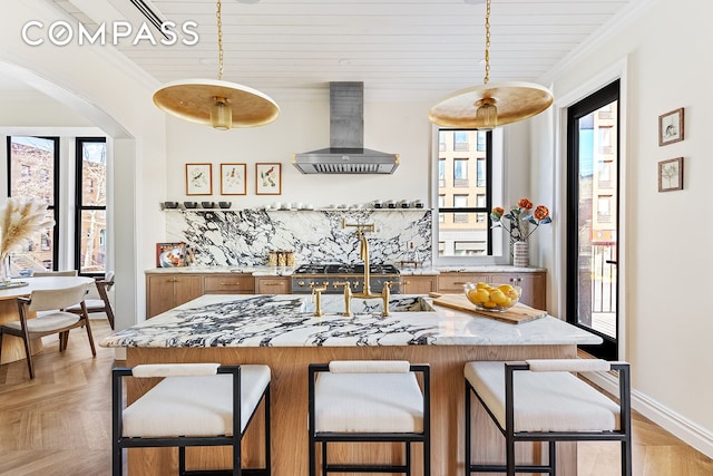 kitchen with ventilation hood, crown molding, decorative backsplash, brown cabinets, and arched walkways