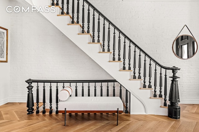 stairs featuring baseboards and brick wall