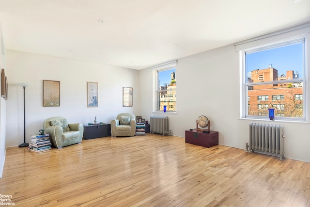 living area with radiator and wood finished floors