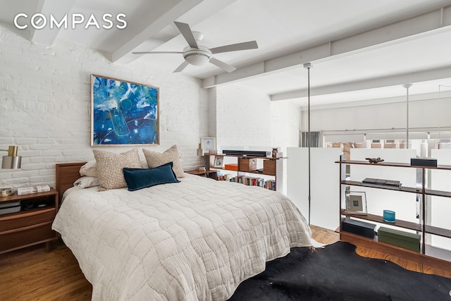 bedroom with ceiling fan, beamed ceiling, brick wall, and wood finished floors