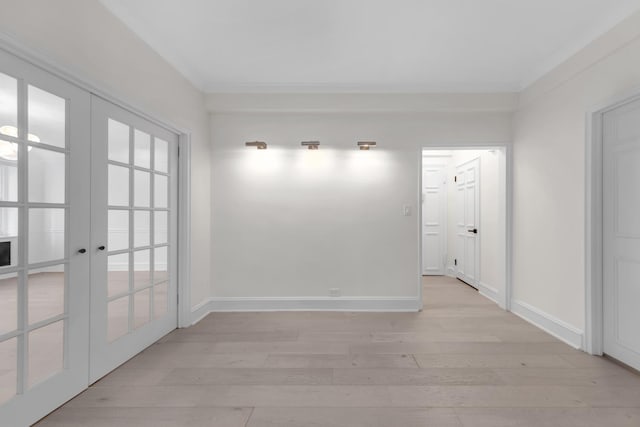 spare room featuring french doors, light wood-style flooring, and baseboards