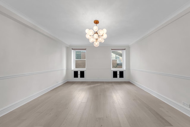 interior space with light wood-style floors, baseboards, a notable chandelier, and ornamental molding