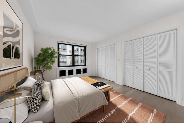 bedroom featuring two closets, baseboards, and wood finished floors