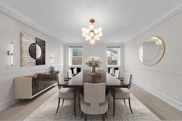 dining space with baseboards, ornamental molding, an inviting chandelier, and light wood-style floors