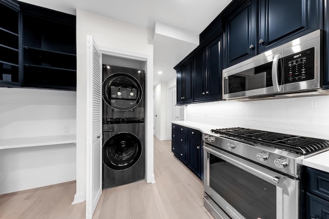 kitchen with stainless steel appliances, stacked washer / dryer, light wood finished floors, and tasteful backsplash