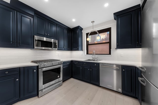 kitchen featuring stainless steel appliances, a sink, light wood-type flooring, decorative backsplash, and pendant lighting