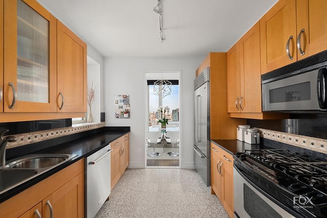 kitchen with stainless steel appliances, baseboards, a sink, and dark countertops