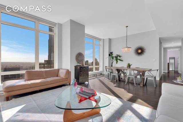 living area with a healthy amount of sunlight, wood finished floors, baseboards, and expansive windows