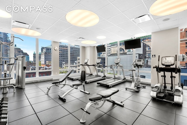 exercise room featuring visible vents, a wall of windows, and a paneled ceiling