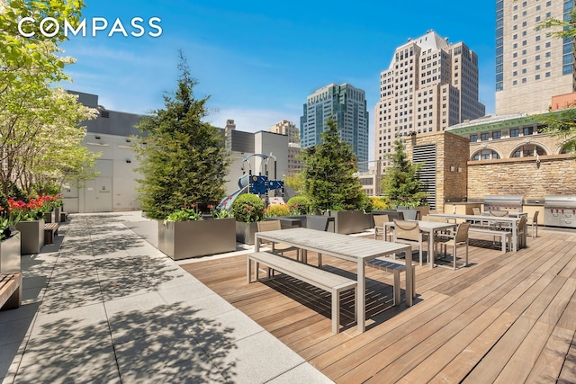 wooden deck featuring a view of city, outdoor dining area, and area for grilling