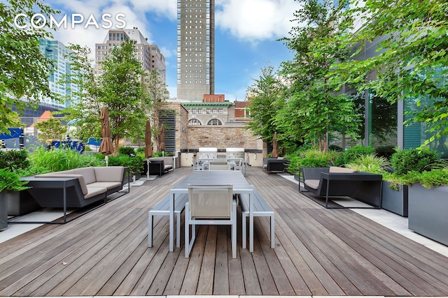 wooden terrace with outdoor dining area, a grill, a view of city, and outdoor lounge area