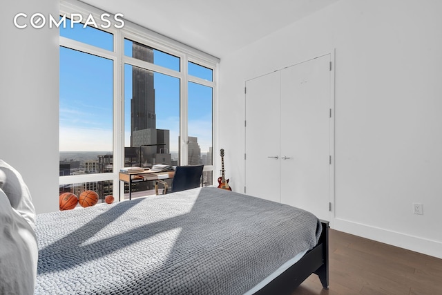 bedroom featuring expansive windows, a closet, dark wood finished floors, and baseboards