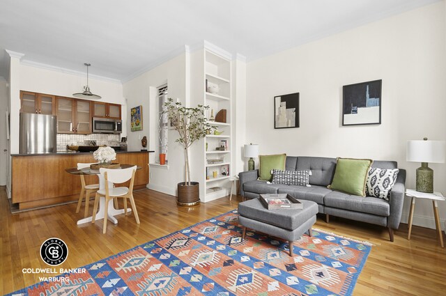 living area with baseboards, radiator, ornamental molding, and hardwood / wood-style flooring