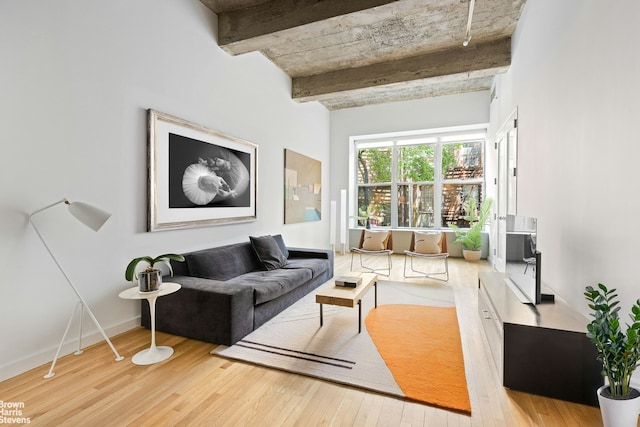 living room featuring baseboards, wood finished floors, and beamed ceiling