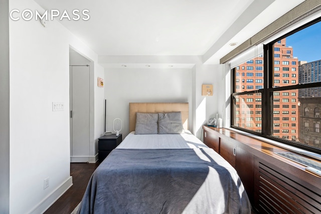 bedroom featuring a view of city, baseboards, and wood finished floors