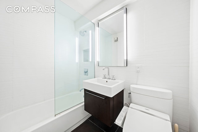 full bath with visible vents, toilet, vanity, enclosed tub / shower combo, and tile walls