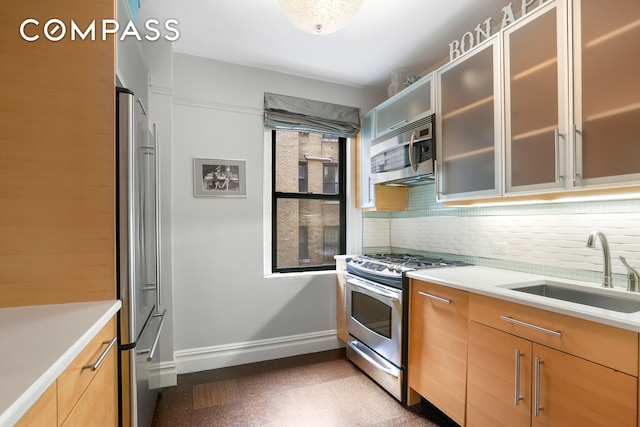 kitchen featuring a sink, baseboards, light countertops, appliances with stainless steel finishes, and decorative backsplash