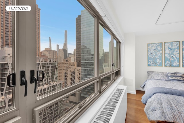 bedroom with baseboards, multiple windows, a city view, and wood finished floors