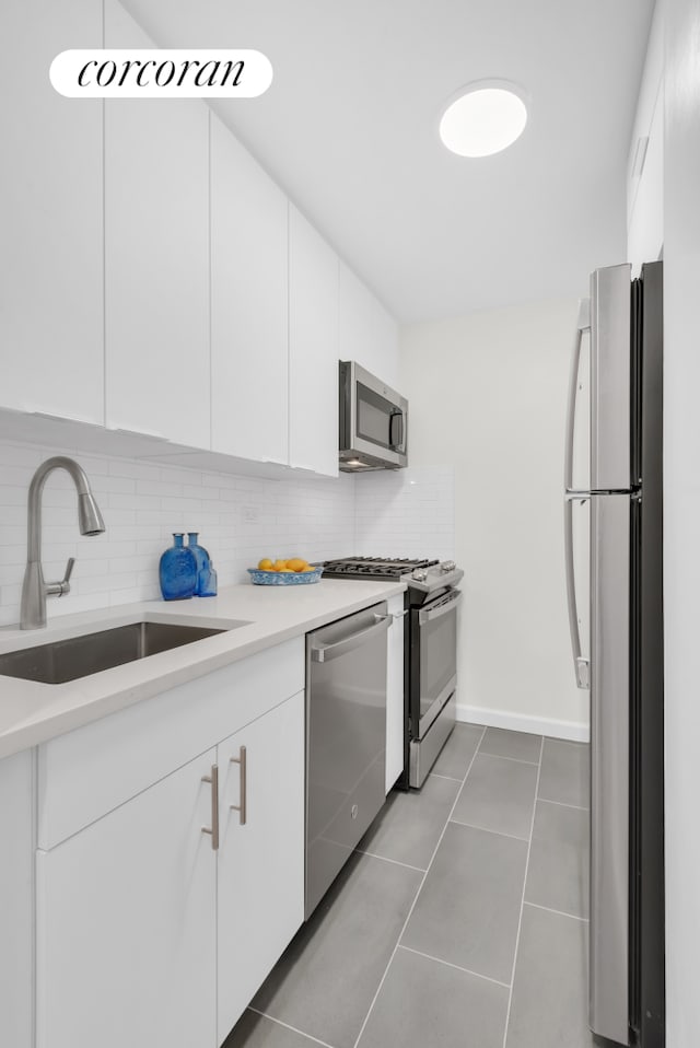 kitchen with tasteful backsplash, light countertops, appliances with stainless steel finishes, white cabinets, and a sink